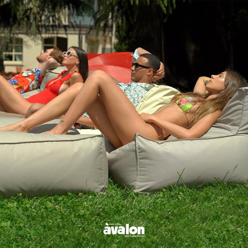 Ragazzi che si rilassano in giardino stesi su divani Avalon Italia